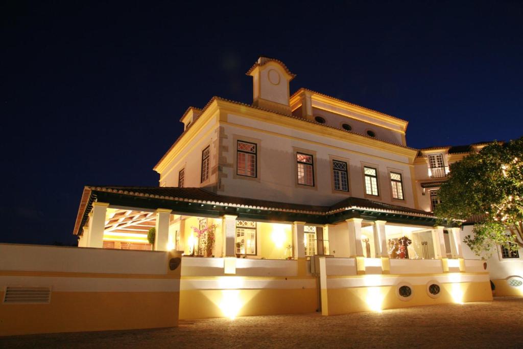 Un grand bâtiment blanc avec des lumières la nuit dans l'établissement Hotel Lusitano, à Golegã