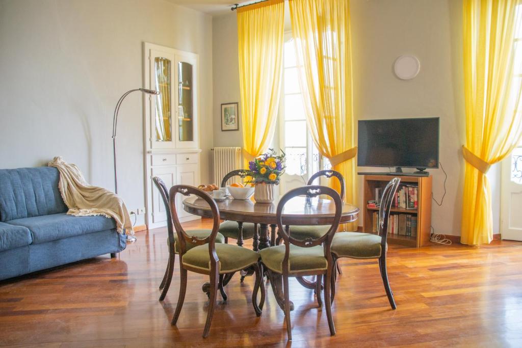 sala de estar con mesa, sillas y sofá azul en Casa Rossana - WelcHome, en Cannobio