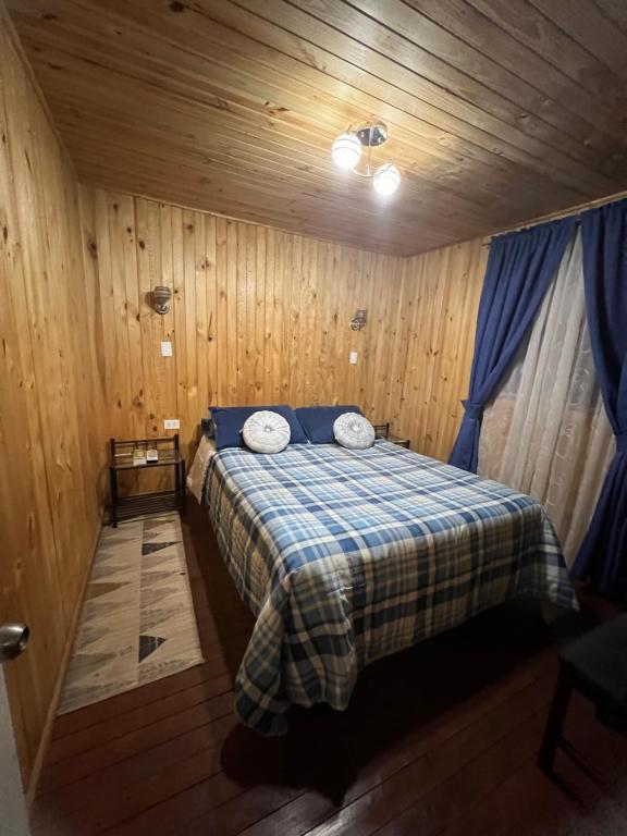 a bedroom with a bed in a wooden cabin at Cabañas Vista Hermosa Radal 7 Tazas in El Torreón