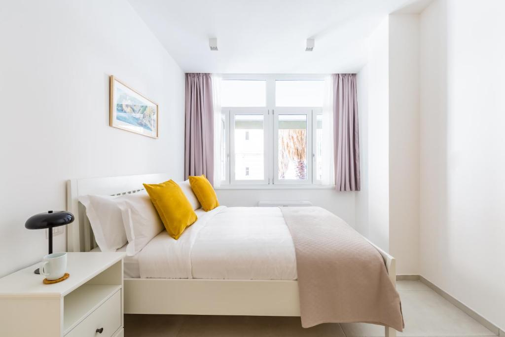 ein weißes Schlafzimmer mit einem großen Bett und gelben Kissen in der Unterkunft Starhost - Mazzini Apartments in Salerno