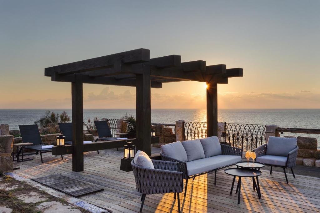 a wooden deck with chairs and a gazebo with the ocean at Luxury Villa over the Cliffs & Wild Beach by FeelHome in Bet Yannay