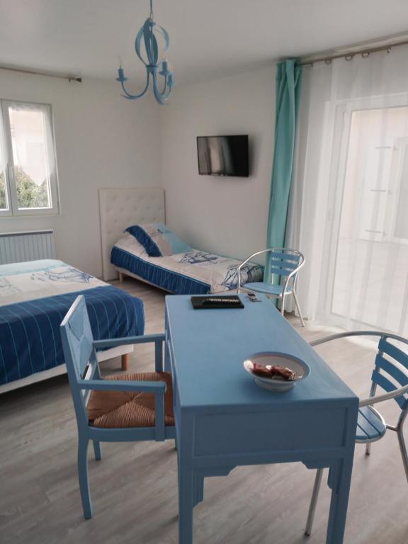 ラ・プレンヌ・シュル・メールにあるbord de merのベッド2台、青いテーブルと椅子が備わる客室です。