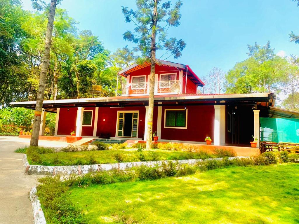 a red house in the middle of a yard at Shrenya Orchidz-Coorg Nature Stay in Madikeri
