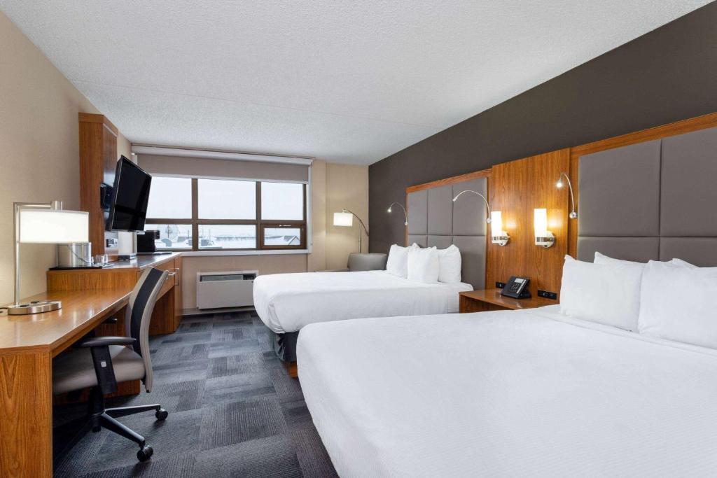 a hotel room with two beds and a desk at Ramada by Wyndham Northern Grand Hotel & Conference Centre in Fort Saint John