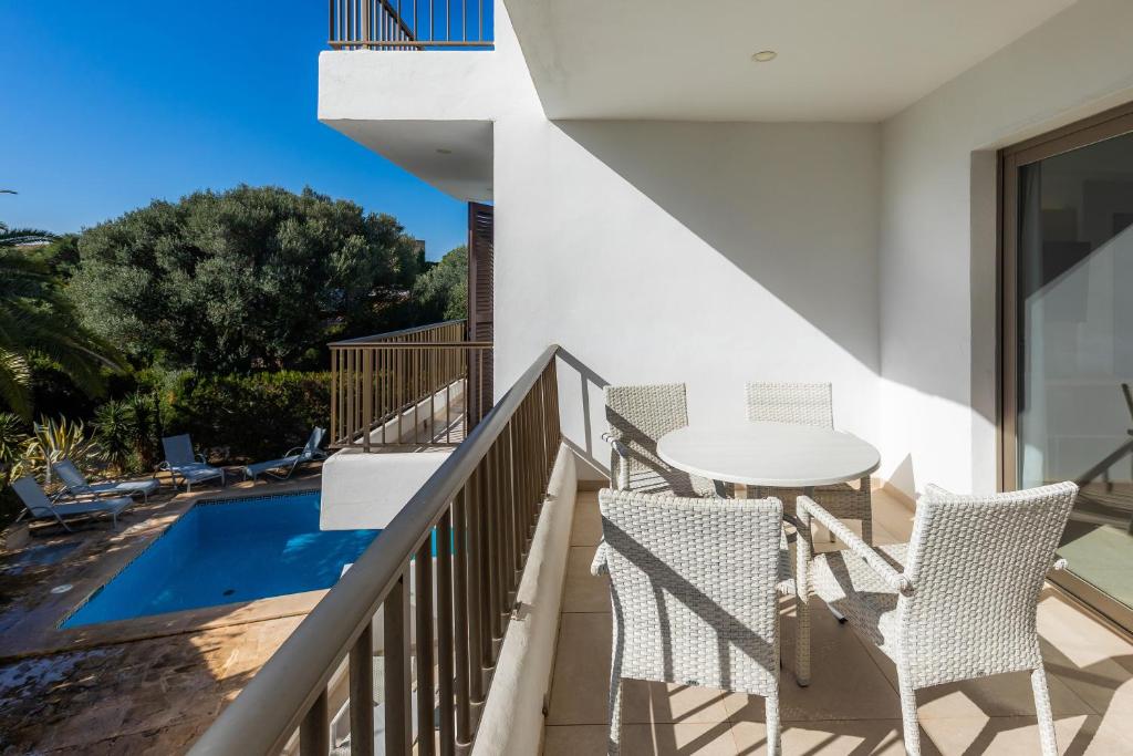 balcón con mesa, sillas y piscina en Apartamento Aquamarina 6, en Cala Ferrera