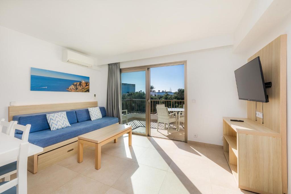 uma sala de estar com um sofá azul e uma varanda em Apartamento Aquamarina 8 em Cala Ferrera
