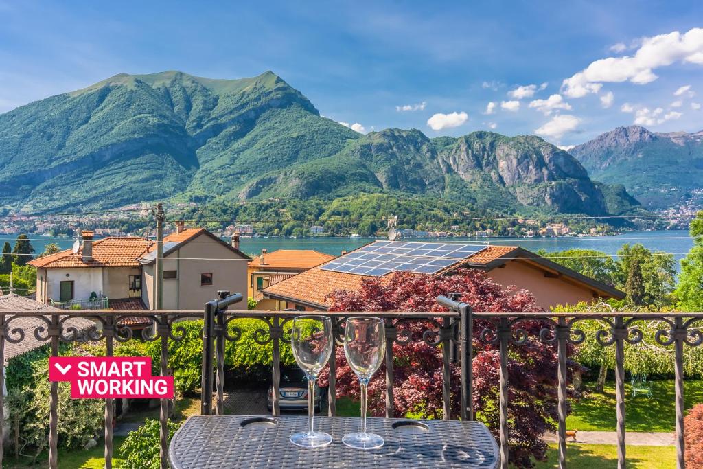 een tafel met wijnglazen op een balkon met bergen bij Villa Gard by Wonderful Italy in Bellagio