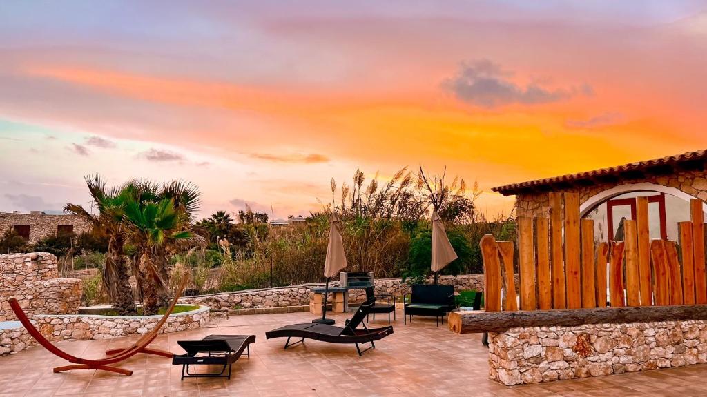 a patio with chairs and a gazebo with a sunset at VILLA CHANTAL in Lampedusa