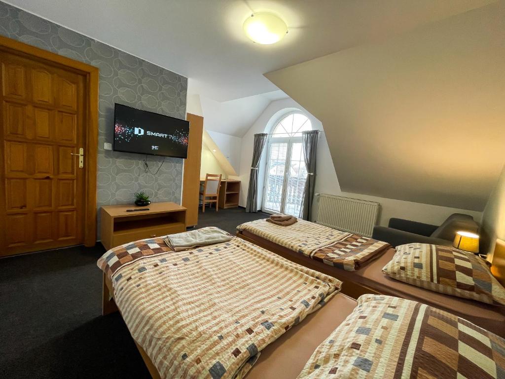 Uničov的住宿－Hotel Aldo，一间卧室设有两张床,墙上配有电视。