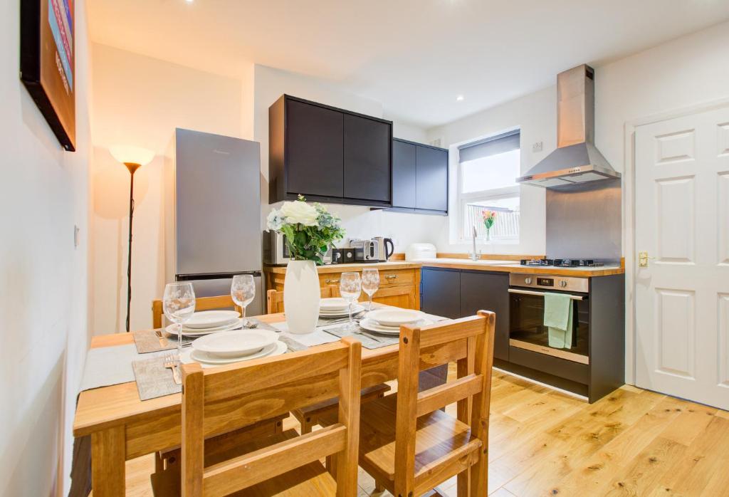 a kitchen with a wooden table with chairs and a dining room at Statera Apartments - 2-Bed House in Stratford in London
