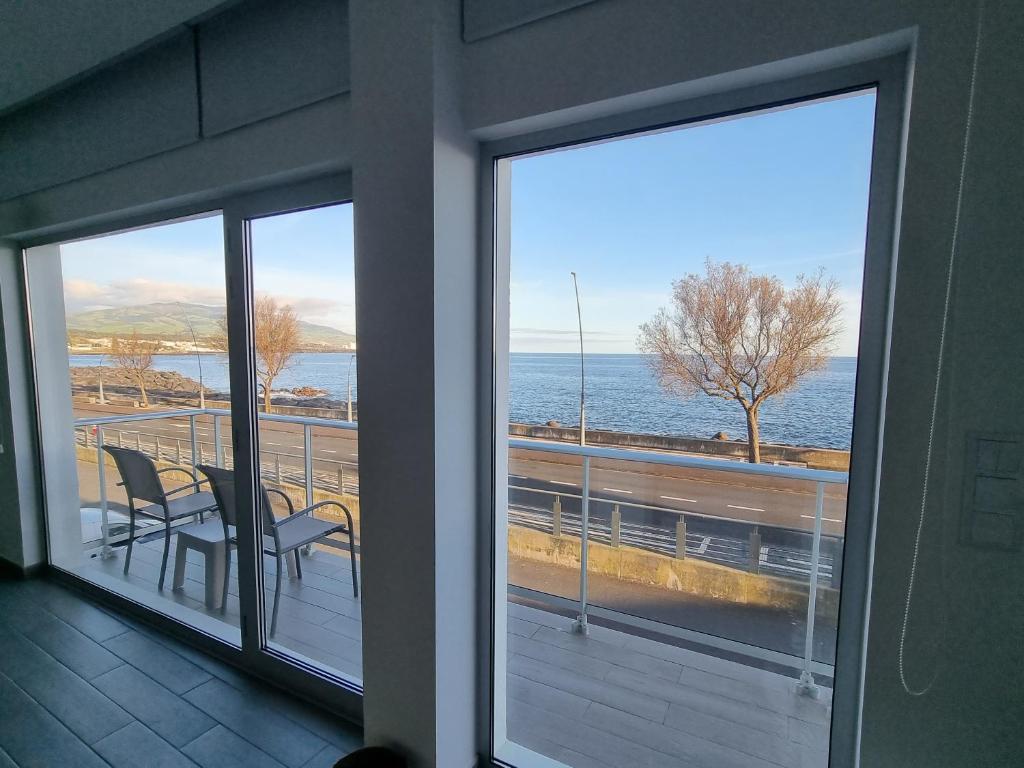 a balcony with two chairs and a view of the ocean at Bay House - Seascape Apartment in Ponta Delgada