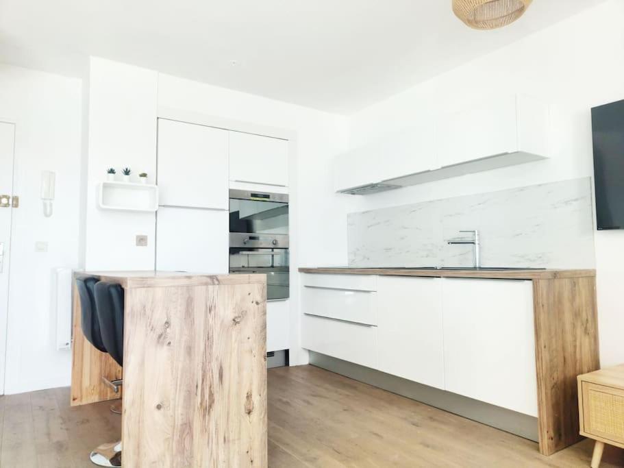 uma cozinha com armários brancos e um balcão de madeira em Beau duplex familial avec jardin clôturé em Douvaine