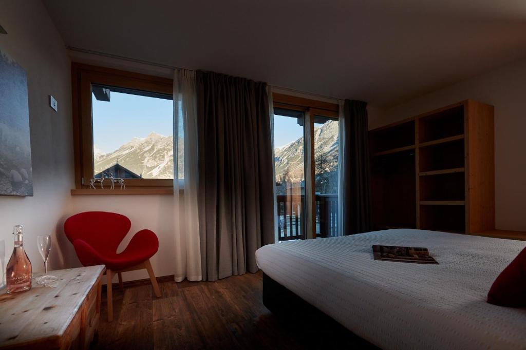 a bedroom with a bed and a chair and a window at Al Bait Ross in Bormio