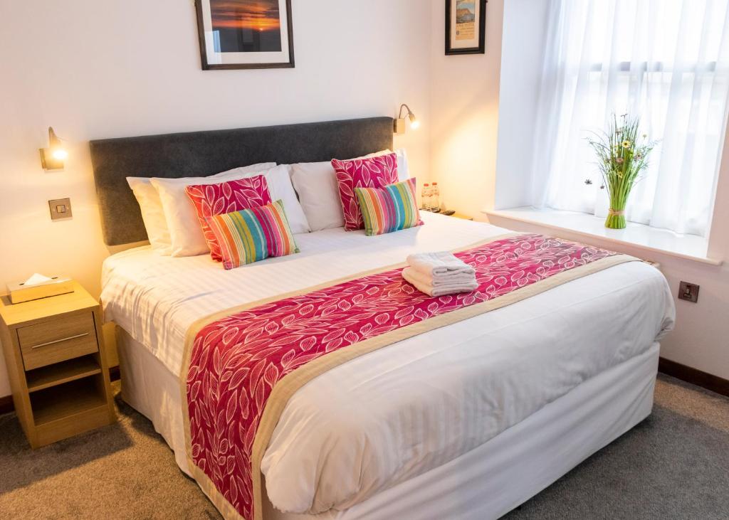 The Rostrevor Inn في روستريفور: غرفة نوم مع سرير كبير مع وسائد ملونة