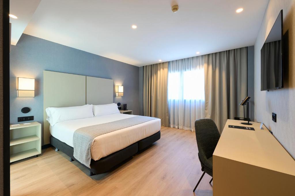 バルセロナにあるCatalonia La Maquinistaのベッドとデスクが備わるホテルルームです。