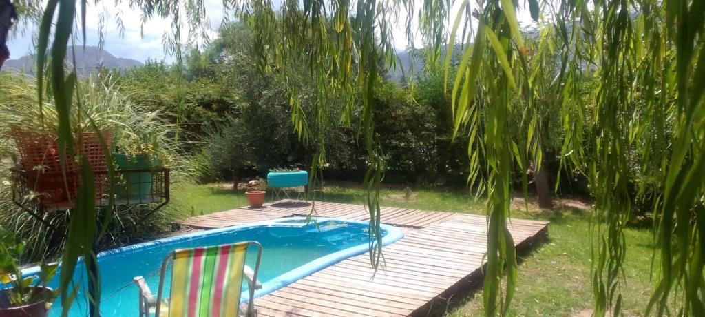 een zwembad met een houten terras en twee stoelen ernaast bij El Descanso de la Yapa in Villa Bustos