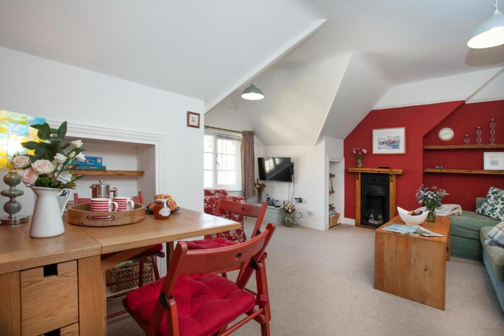 een woonkamer met een tafel en rode muren bij The Roost in Budleigh Salterton