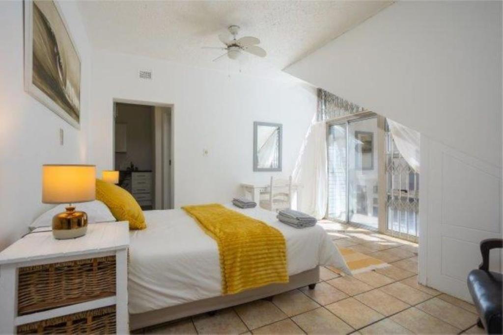 a bedroom with a bed with a yellow blanket at The Villa Umdloti in Umdloti