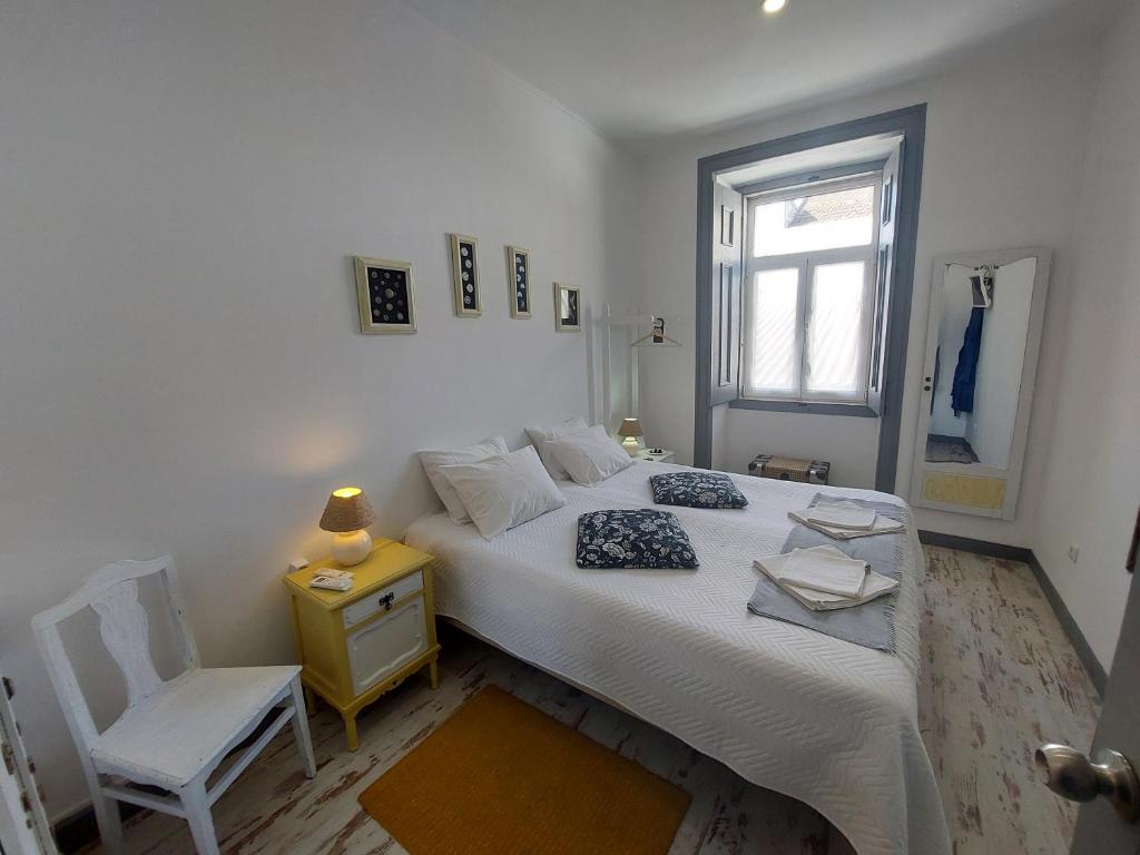 a bedroom with a bed and a chair and a window at Casa Velha in Alenquer