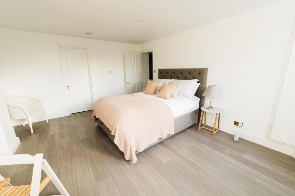 a white bedroom with a bed and a chair at New - Bright - Fresh - with Parking in Bath