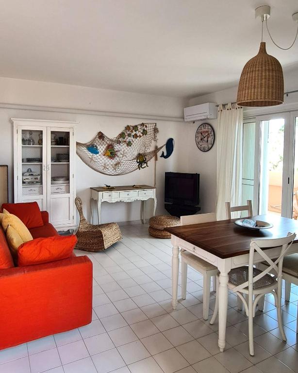 a living room with a table and a red couch at Il Poggiolo di Levante - Piscina e Ombrellone spiaggia prima fila incluso in Marcelli