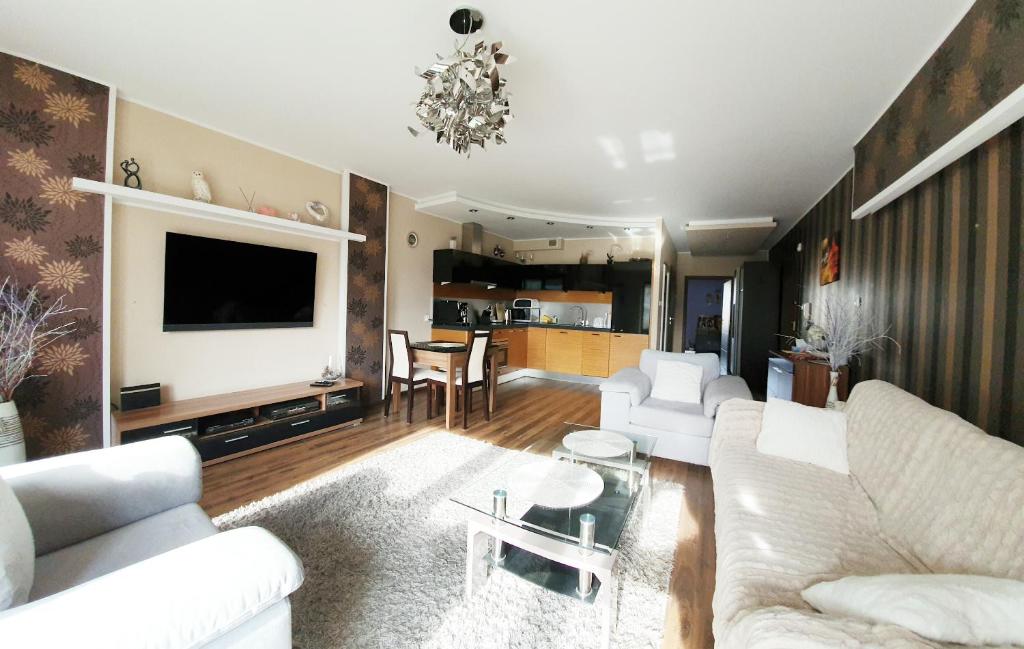 a living room with white couches and a tv at Apartment Gdańsk Seaside & City Center in Gdańsk