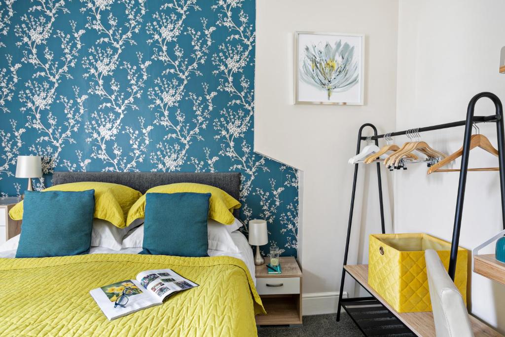 a bedroom with a yellow bed with blue and white wallpaper at Cherwood Guest House in Paignton