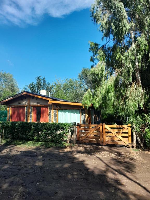 una casa con una valla de madera y una puerta en Aldea Hippie en Los Reartes