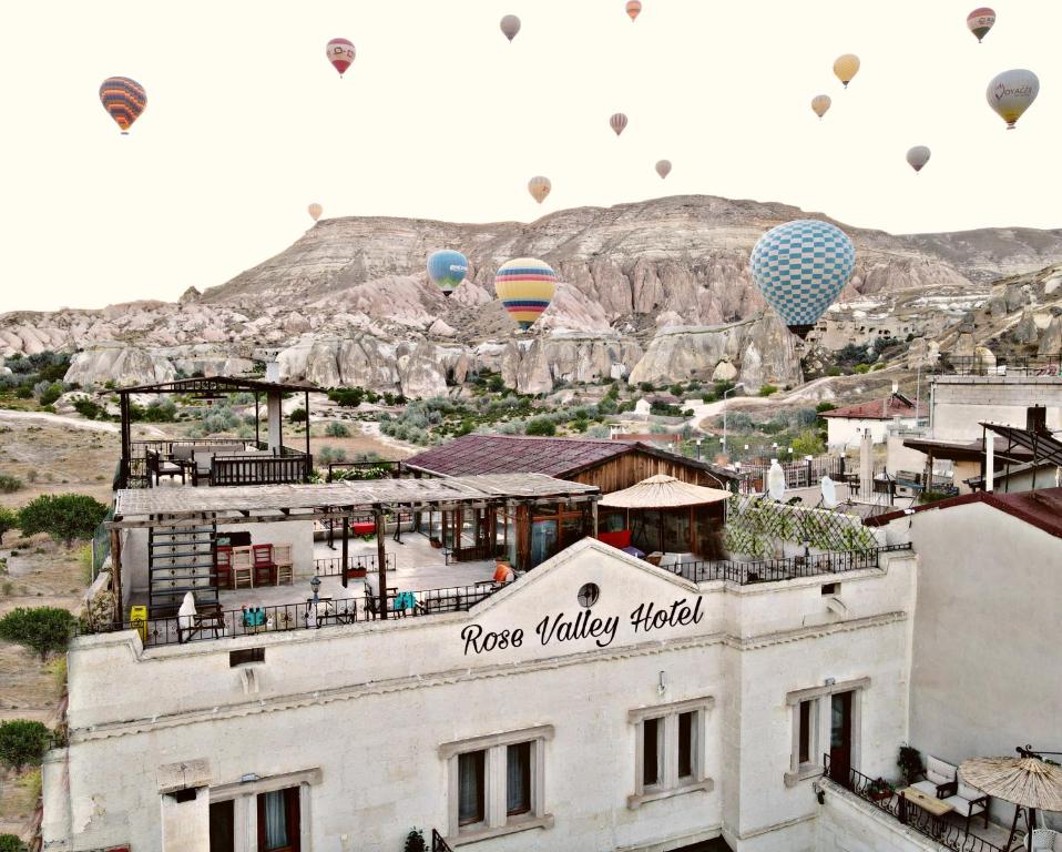 a group of hot air balloons flying over a building at Rose Valley Hotel in Göreme