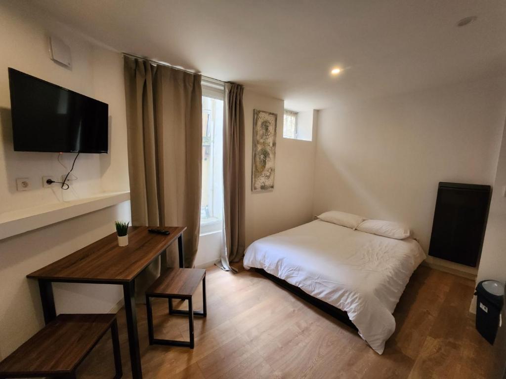 1 dormitorio con cama, mesa y TV en Studio calme rdc coté cours en Bar-le-Duc