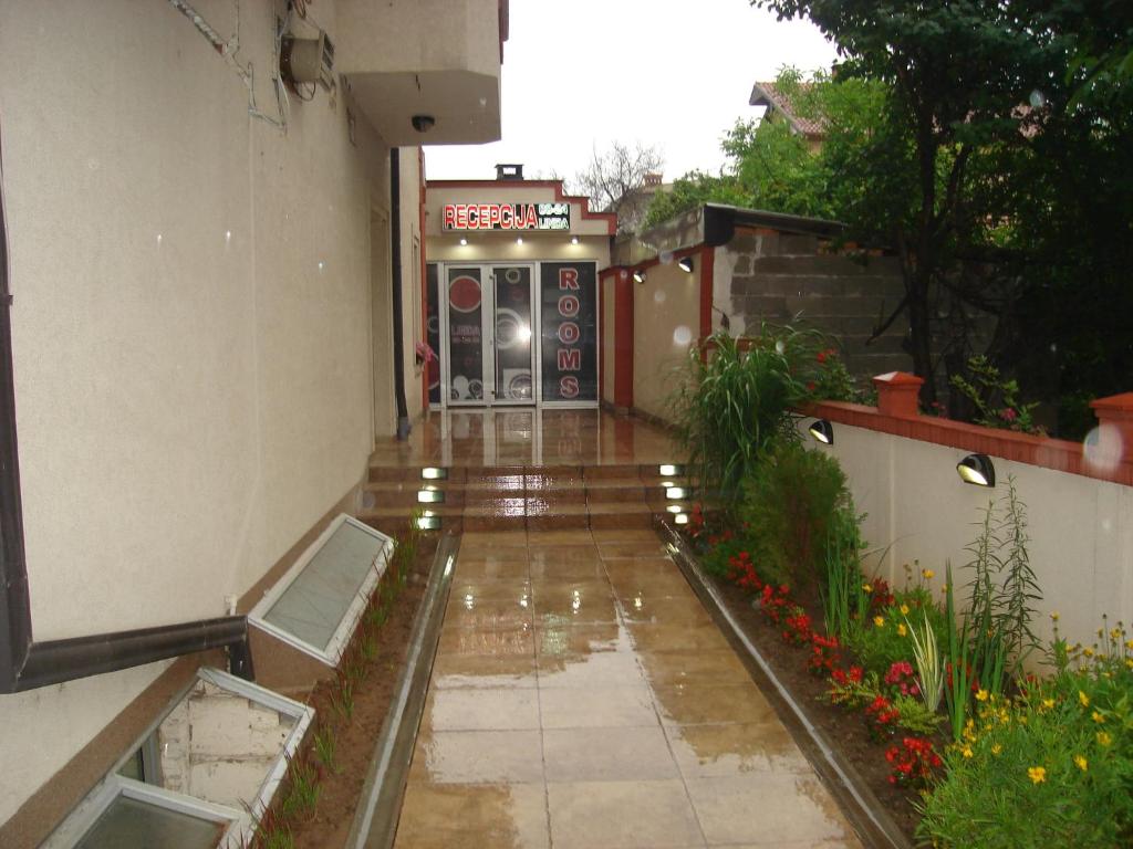 une passerelle imprégnée de pluie menant à un bâtiment avec porte dans l'établissement Linda Bed and Breakfast, à Niš