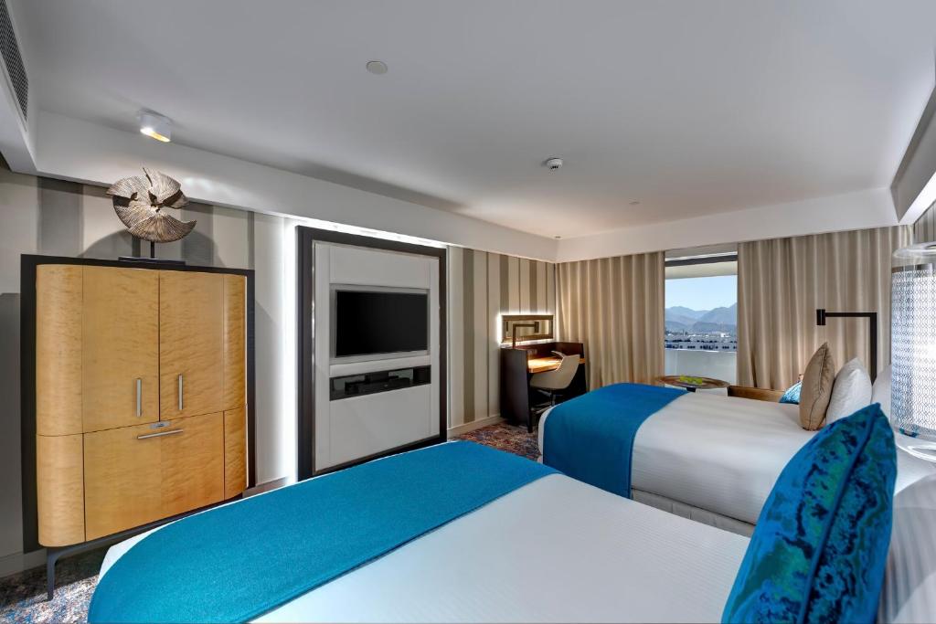 a hotel room with two beds and a television at InterContinental Muscat by IHG in Muscat
