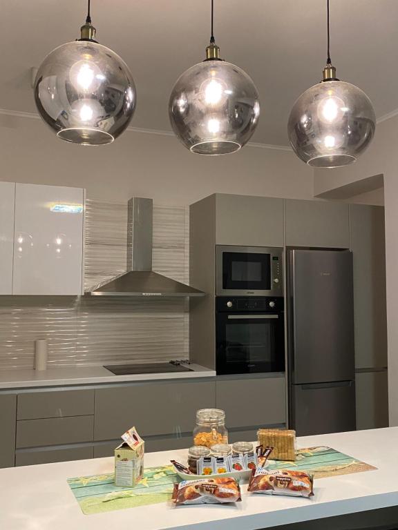 uma cozinha com electrodomésticos de aço inoxidável e candeeiros de prata pendentes em SEA HORIZON SUITES em Chalkida