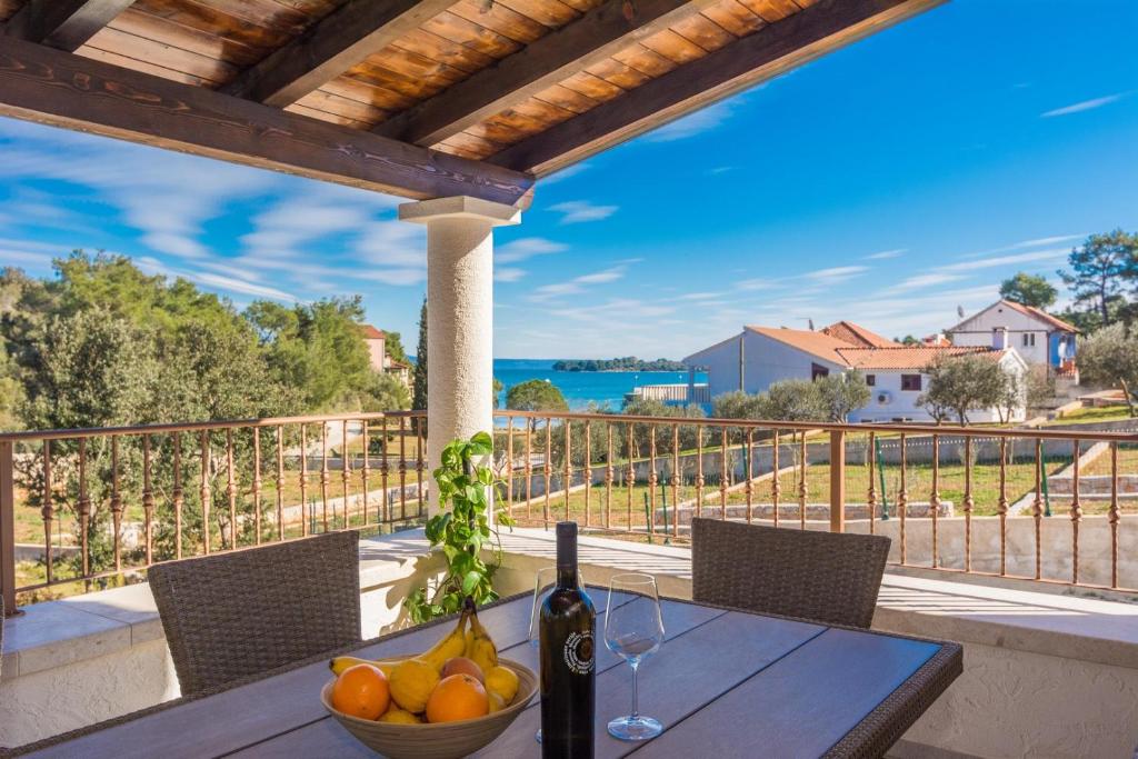 a table with a bowl of fruit and a bottle of wine at Holiday Home Irena-Adriatic Luxury Villas in Žman
