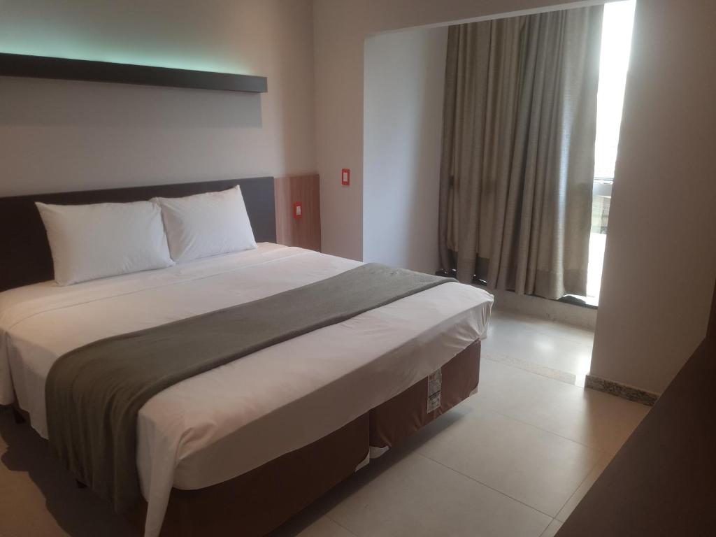 - un grand lit dans une chambre avec une grande fenêtre dans l'établissement HOTEL BRASIL, à Boa Esperança