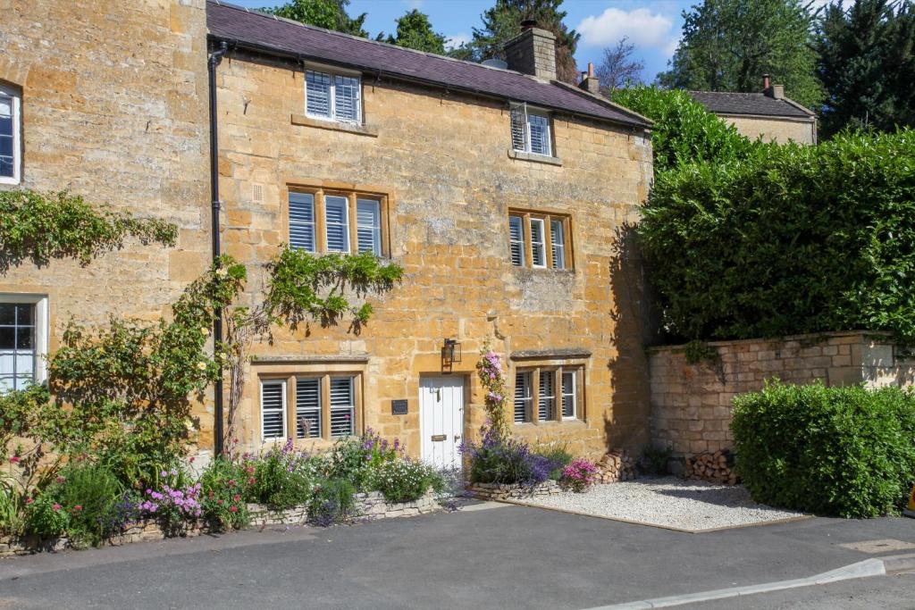 an old brick house with flowers in front of it at Sage Cottage in Blockley