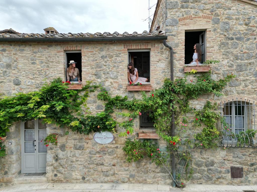 personnes assises dans les fenêtres d'un vieux bâtiment en pierre dans l'établissement Antica Dimora, à San Gimignano