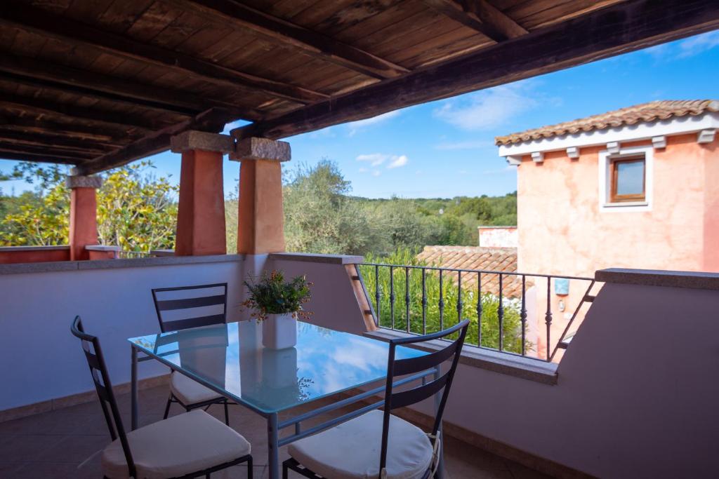 een balkon met een glazen tafel en stoelen bij Residenze Il Girasole in Golfo Aranci