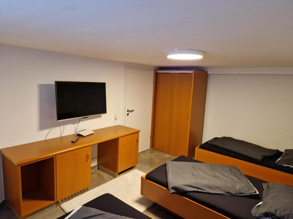 a room with two beds and a desk with a television at Monteurzimmer-mit GemeinschaftsBad und Küche BEI RASTATT in Muggensturm