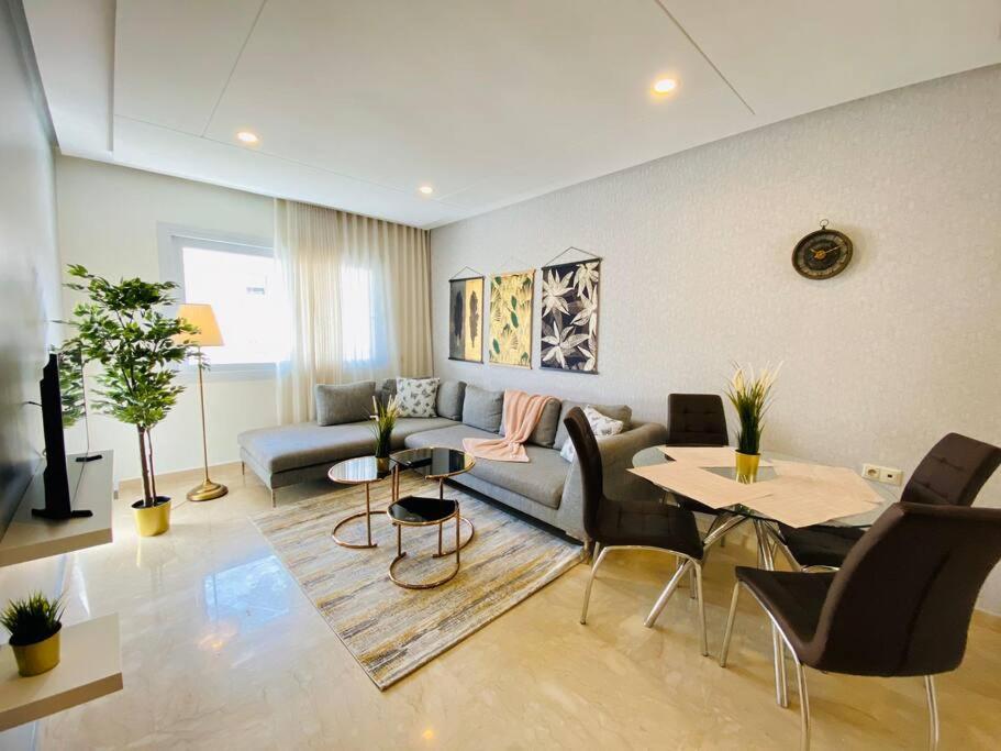 Una sala de estar con un sofá, una mesa y sillas. en Cosy Triangle D Or Bourgogne - By AppartAli, en Casablanca