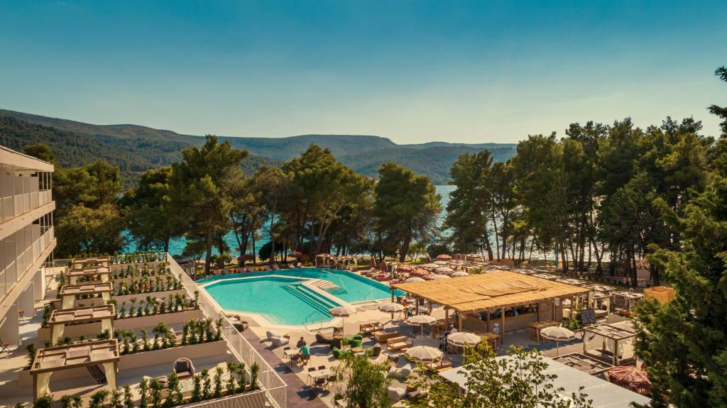 een uitzicht op een resort met een zwembad en tafels en stoelen bij PLACES Hvar Hotel by Valamar in Stari Grad