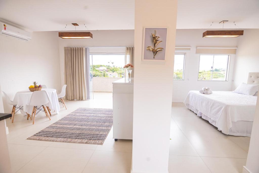 a white bedroom with a bed and a table at APART LAGOA BUZIOS- centro in Búzios