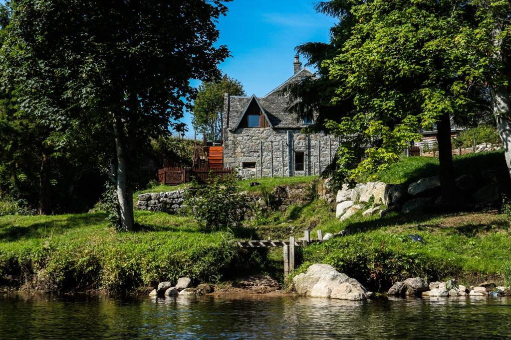 uma casa velha ao lado de um rio em Old Mill On The Spey em Boat of Garten