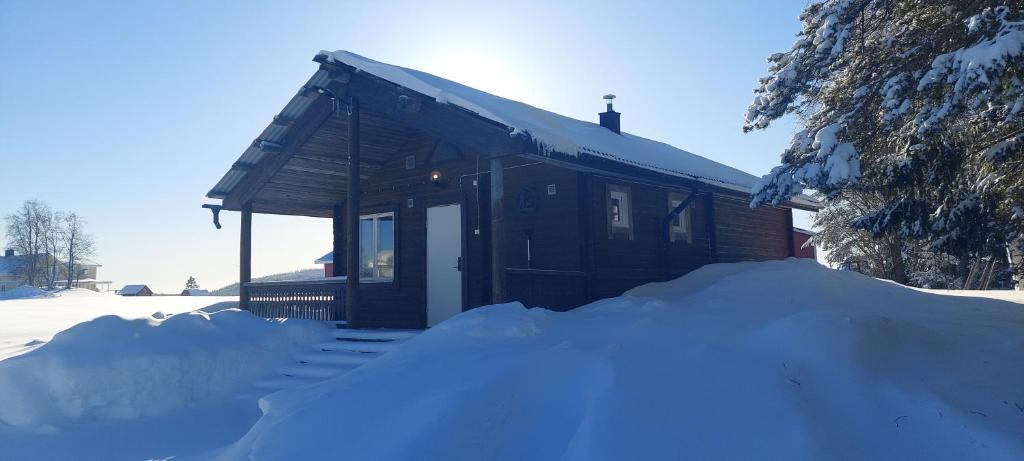 una pequeña cabaña con una pila de nieve delante de ella en Lönås, en Håptjärnliden