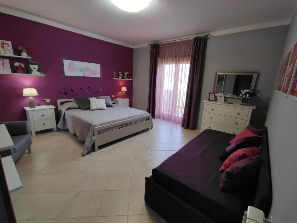 - une chambre avec des murs violets, un lit et un canapé dans l'établissement Il Giardino delle Zagare, à Fondi