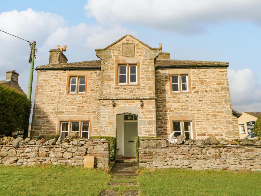 an old stone house with a stone wall at Manor House in Leyburn