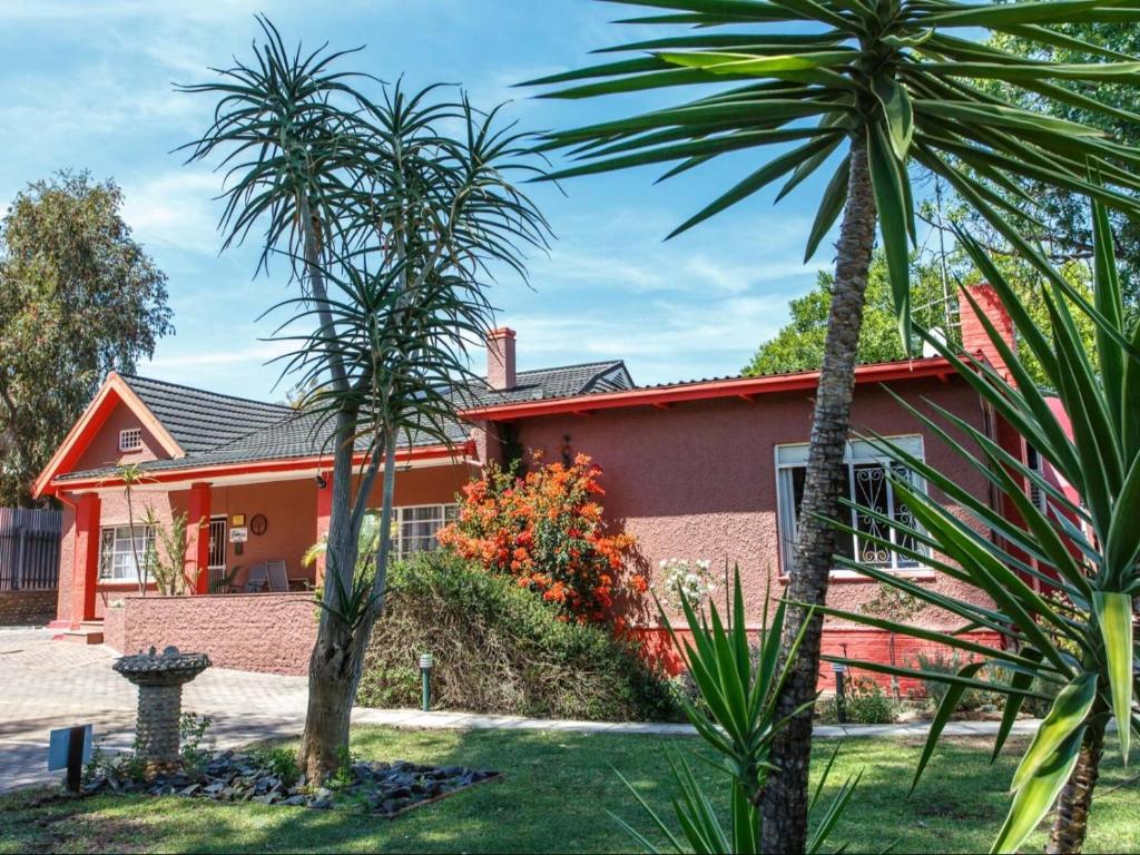 uma casa com duas palmeiras em frente em Gumtree Guest House em Oudtshoorn