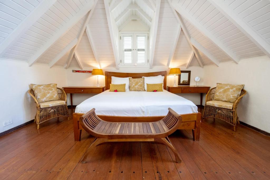 a bedroom with a large bed and two chairs at Sirena Bay Estate in Willemstad
