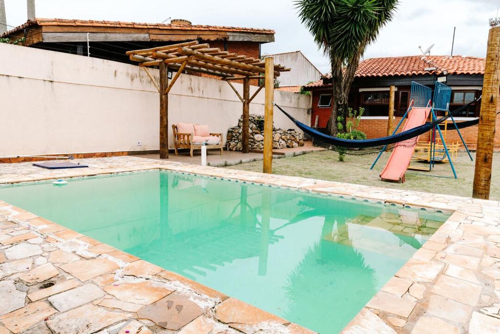 a swimming pool with a hammock and a house at Casa c conforto piscina e churrasqueira Atibaia in Atibaia