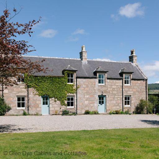 uma grande casa de pedra com hera a crescer nela em Cuttieshillock em Banchory